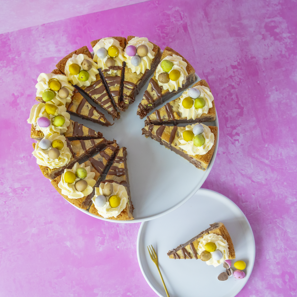 Decorative cake for Easter party with a slice placed on a white plate on a pink background