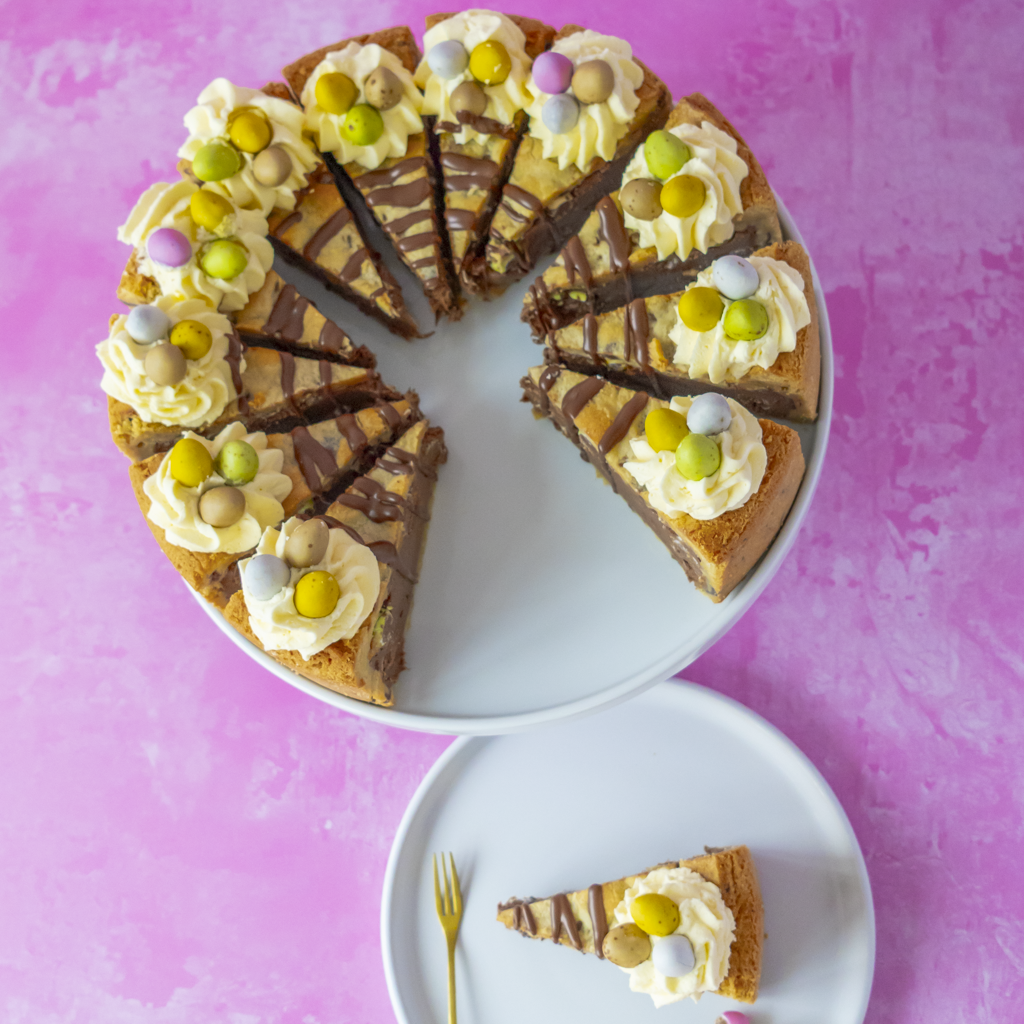 Decorative Easter egg cake with a slice removed on a pink background