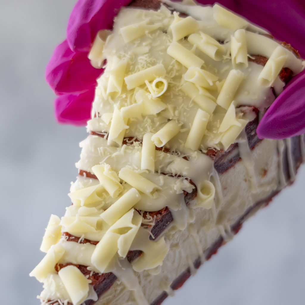 Close-up of DoughGirl Red Velvet Cookie Pie Slice with white chocolate curls