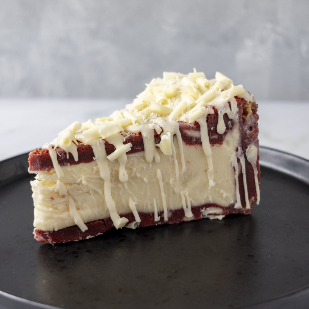 DoughGirl Red Velvet Cookie Pie Slice served on black plate with white chocolate curls