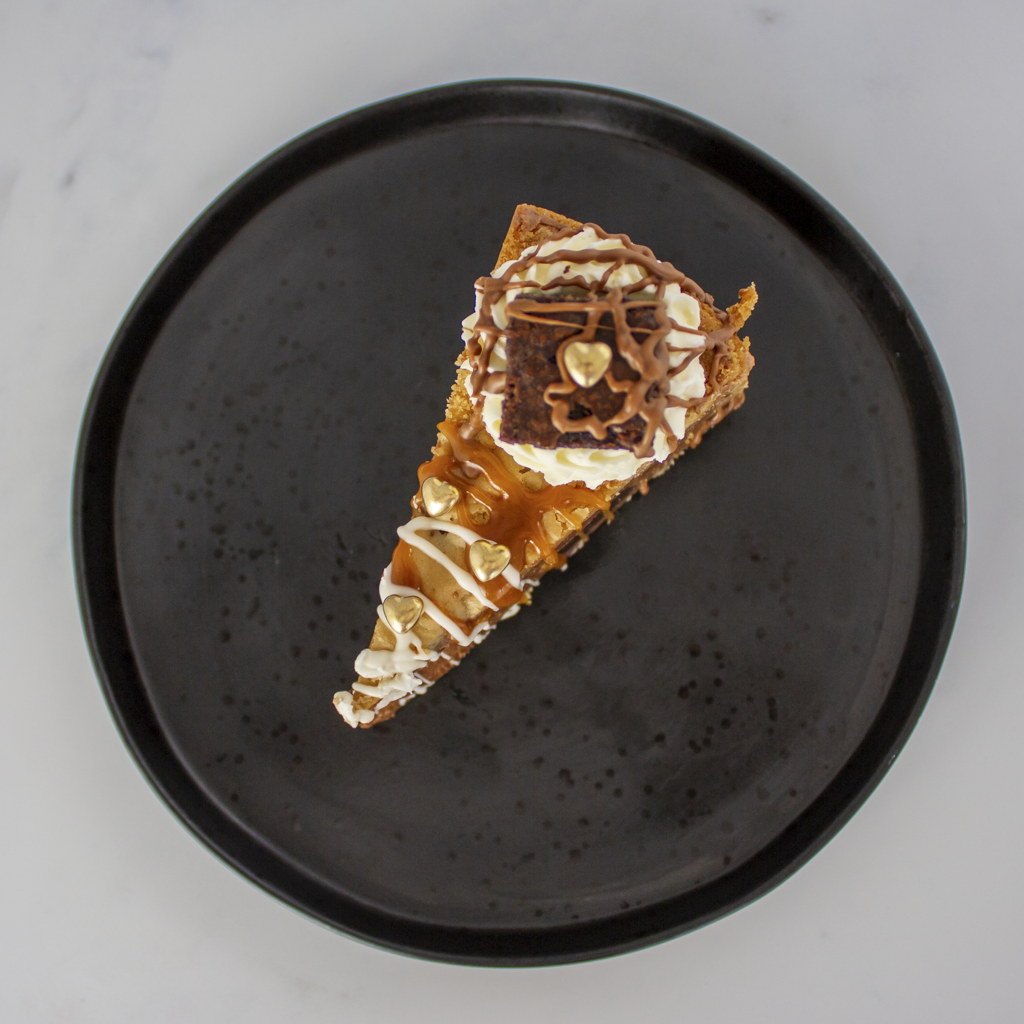 Slice of layered dessert on a black plate with a gray background