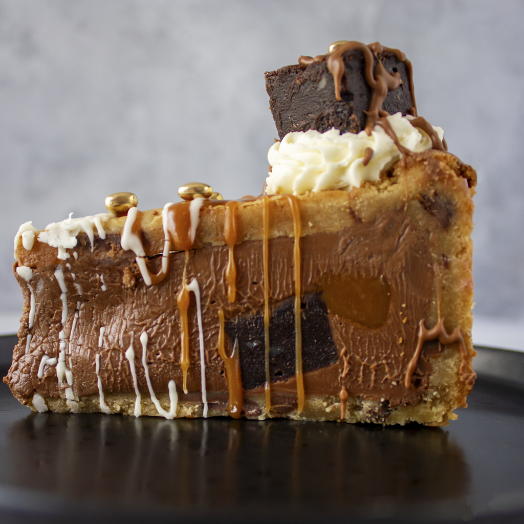 Limited Edition Salted Caramel Brownie Cookie Pie by DoughGirl UK with chocolate, caramel, and white cream on a gray background