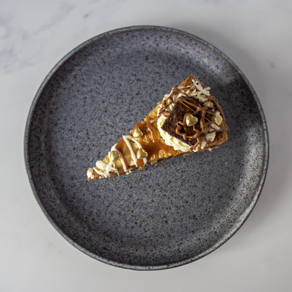 Limited Edition Salted Caramel Brownie Cookie Pie with golden heart Valentine decoration on a dark speckled plate with a light gray background