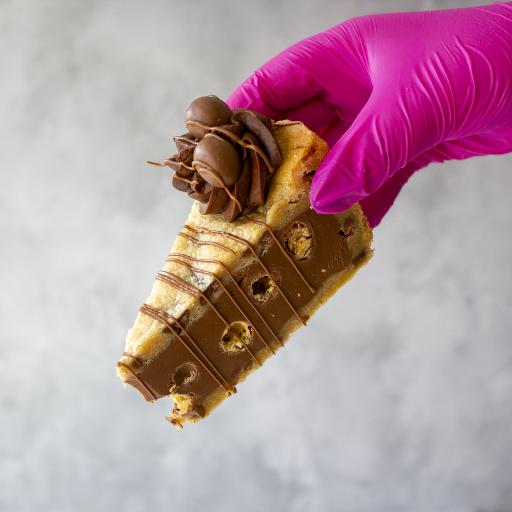 Hand holding a piece of chocolate-covered dessert with a white background