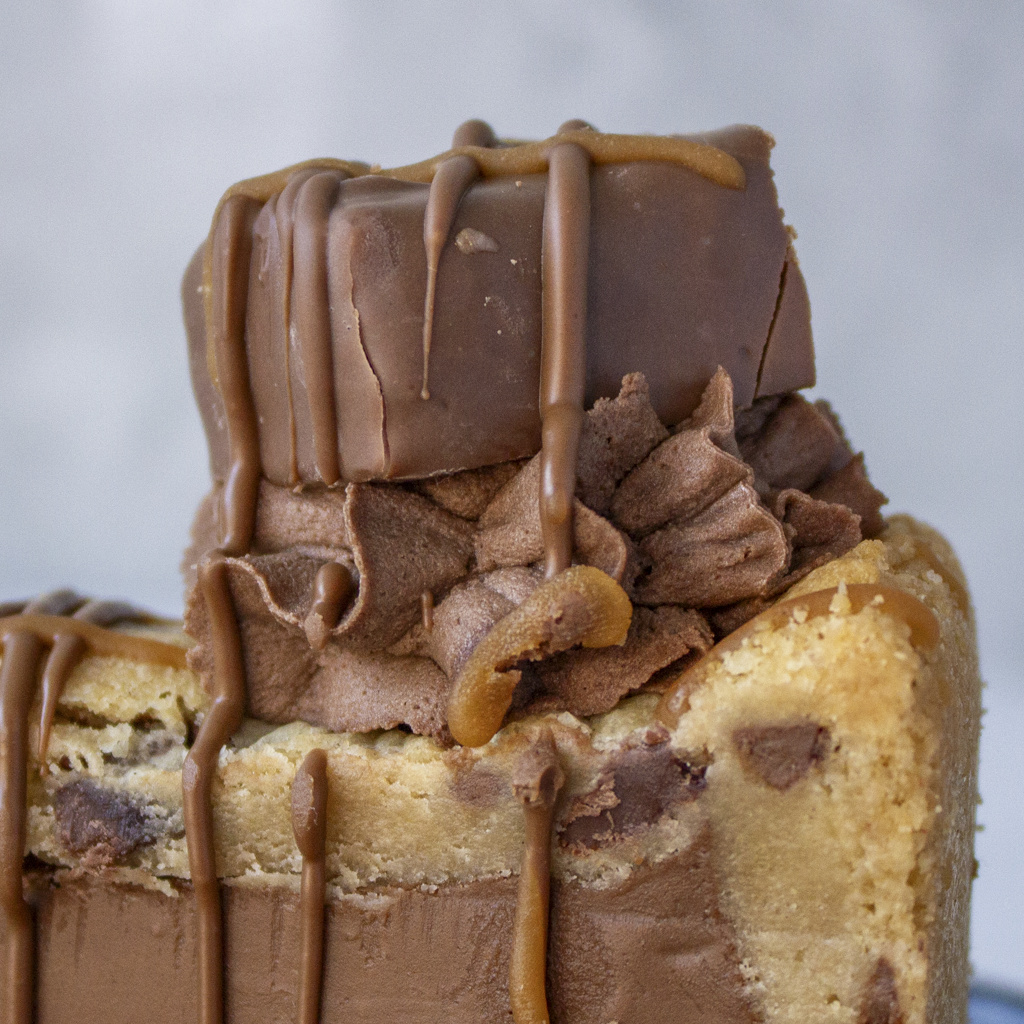 Close-up of Snickers Cookie Pie Slice with chocolate buttercream and Snickers pieces