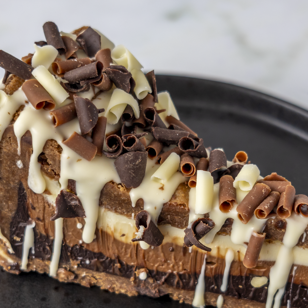 Side close-up of Triple Chocolate Cookie Pie Slice with white chocolate drizzle and curls
