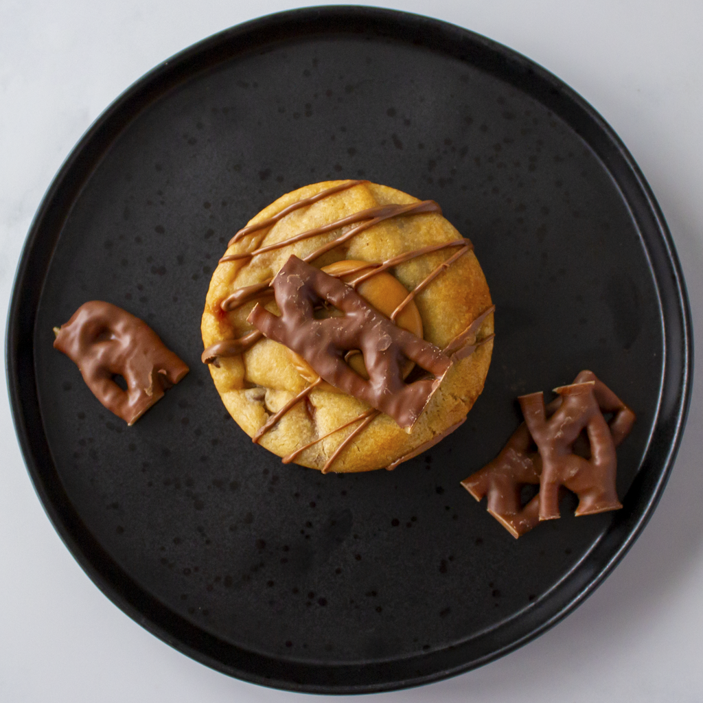 DoughGirl Curly Wurly Deluxe Cookie on black plate with chocolate bar pieces
