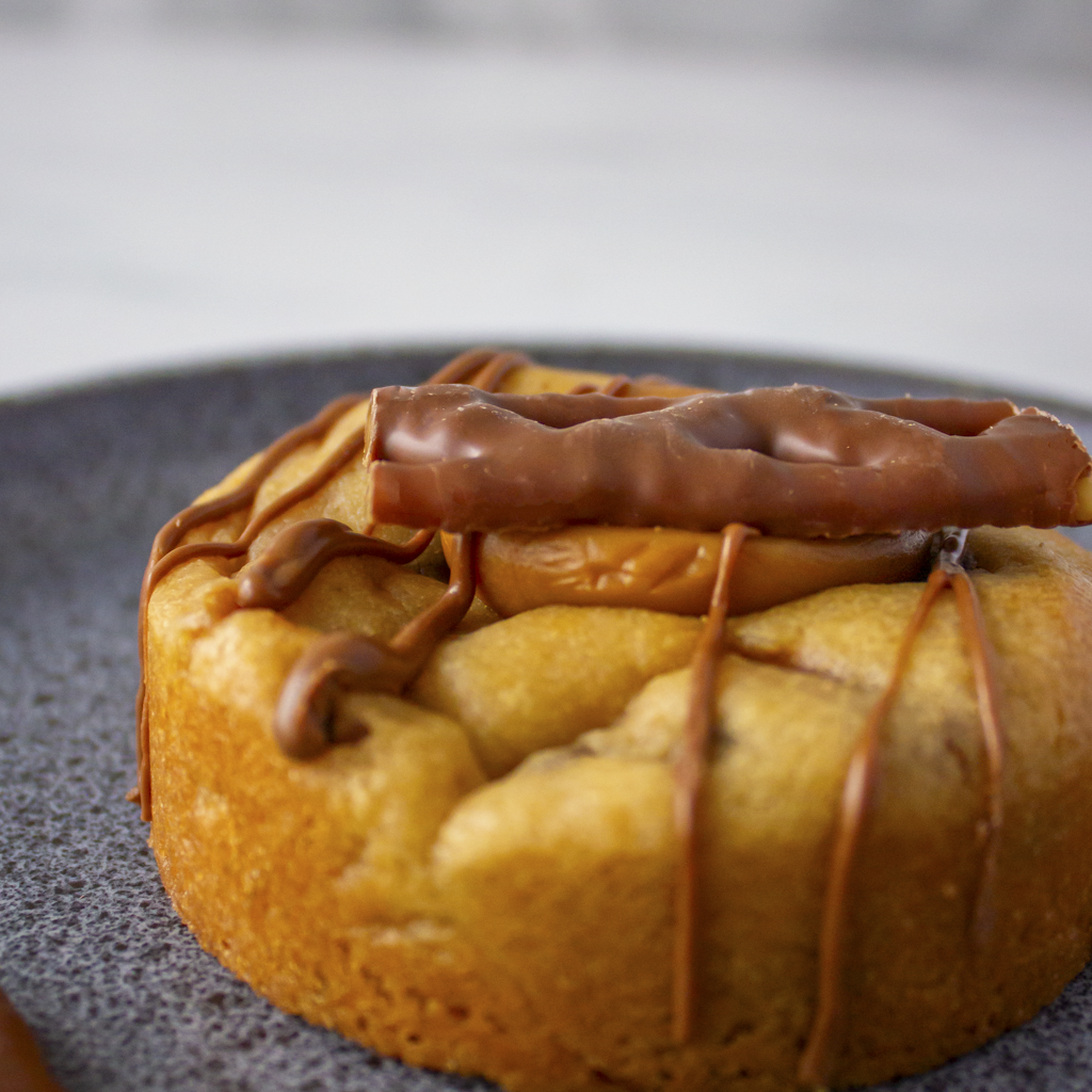 Side view of DoughGirl Stuffed Deluxe Cookie with Curly Wurly and caramel sauce