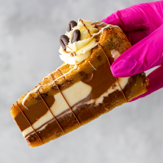 Hand holding a Caffè Latte Cookie Pie by DoughGirl with pink glove on a gray background