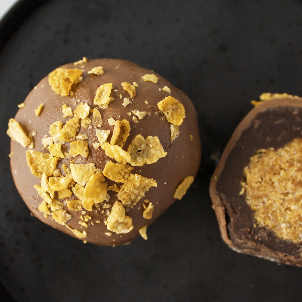 Chocolate Boom Bites with golden caramel cornflake centre on a dark surface