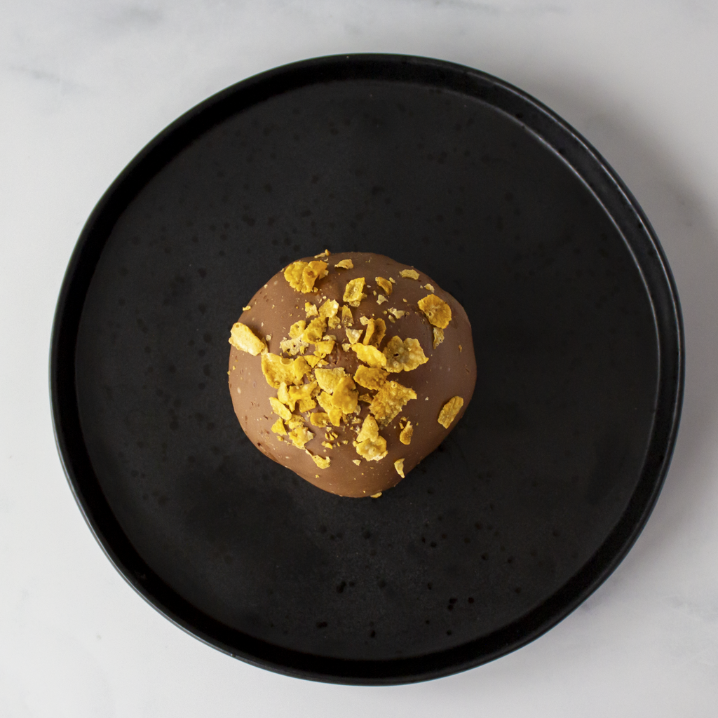 DoughGirl Caramel Cornflake Cracker Choccy Boom Bites with cornflakes on a black plate against a light background
