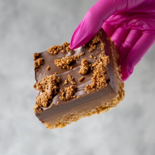 Cracking Caramel Crispie Slab held by a hand in a pink glove on a neutral background