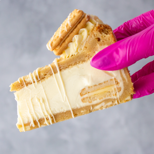 Slice of Custard Cream Dream Cookie Pie held by a hand wearing a pink glove against a gray background