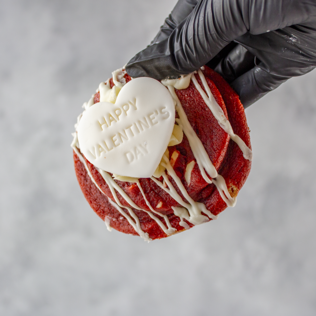 Valentine's Red Velvet Deluxe Cookie with white chocolate drizzle and a 'Happy Valentine's Day' heart on a gray background.
