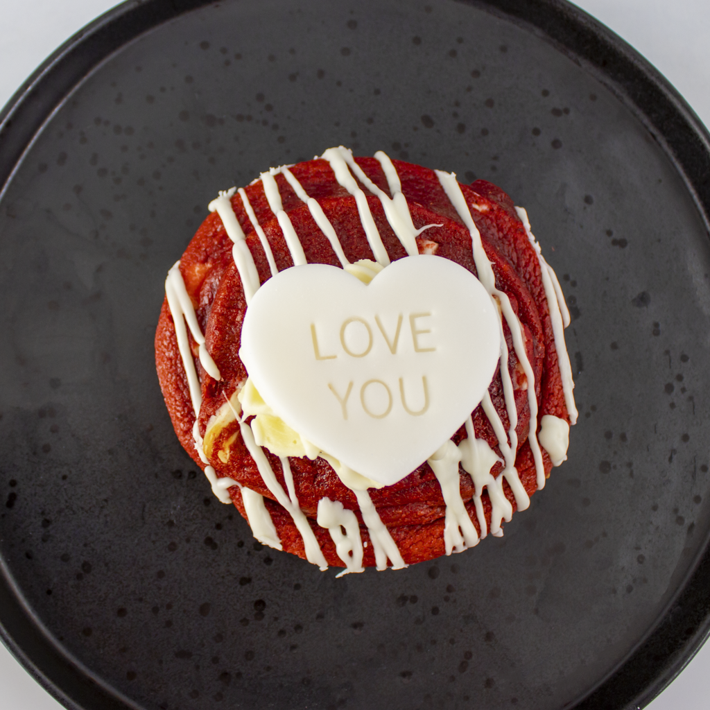 Limited Edition Valentine's Red Velvet Deluxe Cookie with white icing and 'LOVE YOU' heart on a black plate