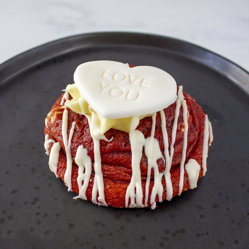 Red velvet deluxe cookie with white cream and 'I LOVE YOU' heart on a black plate. Ideal gift for Valentine day.