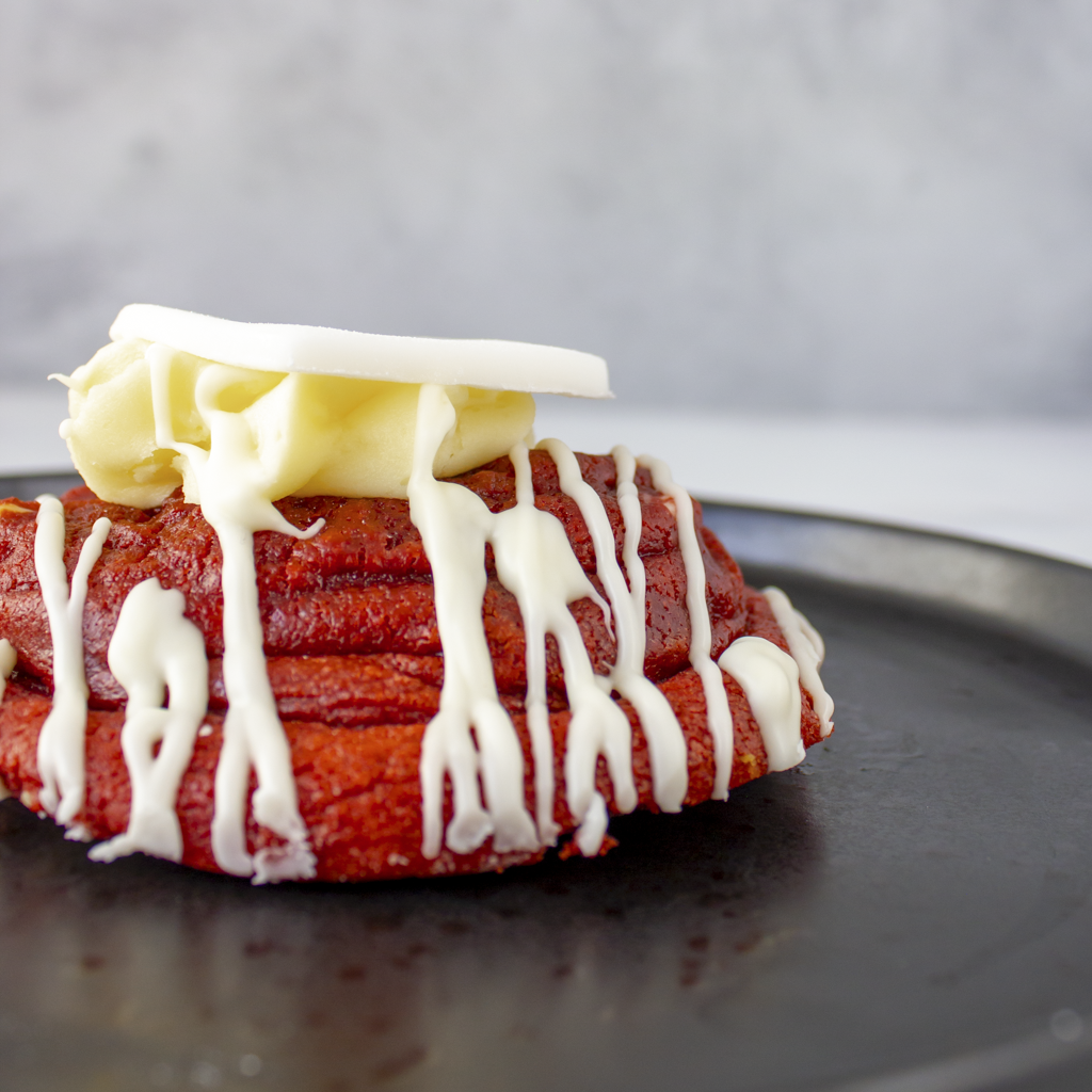 Close-up a red velvet dough cookie with white chocolate frosting on a dark surface