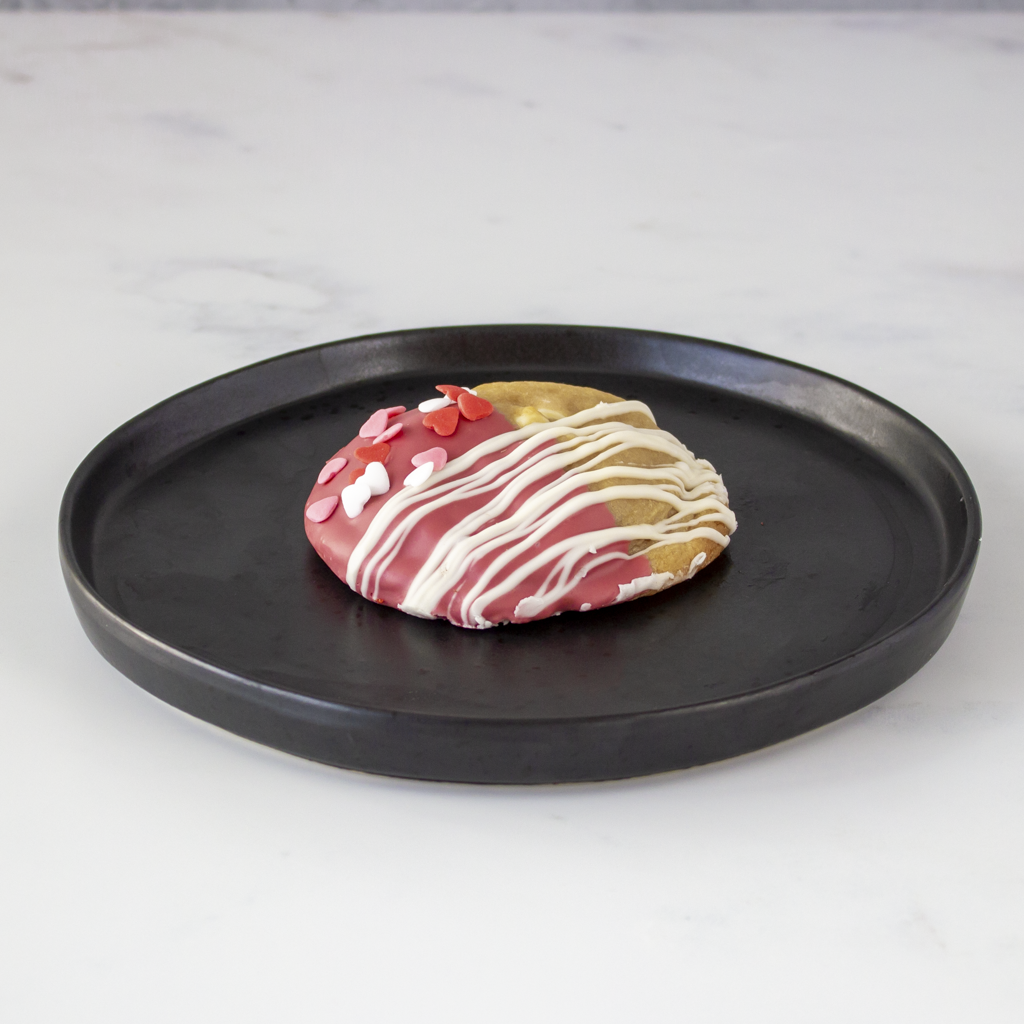 Decorative Valentine pink pastry on a black plate with a white background