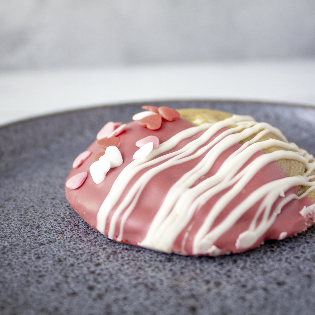 Pink and white cookie pie on a dark gray plate with a blurred background