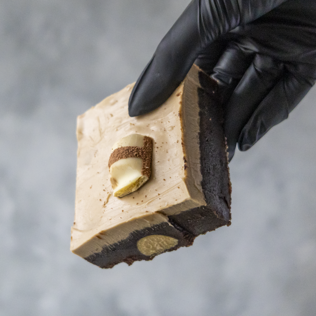 Hand holding a DoughGirl Bueno Brownie Slab with a blurred gray background