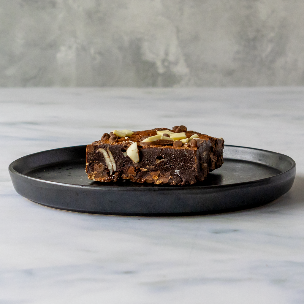 Triple Chocolate Brownie Slab on a black plate against a marble background. Ideal for father's day, Christmas, and sending cookie gifts.