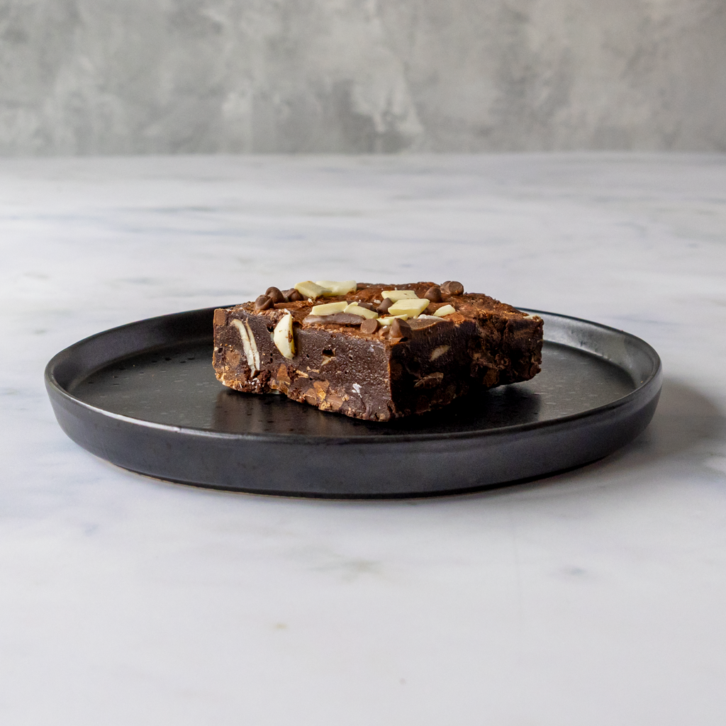 Chocolate dessert with chocolate chips on a black plate against a marble background