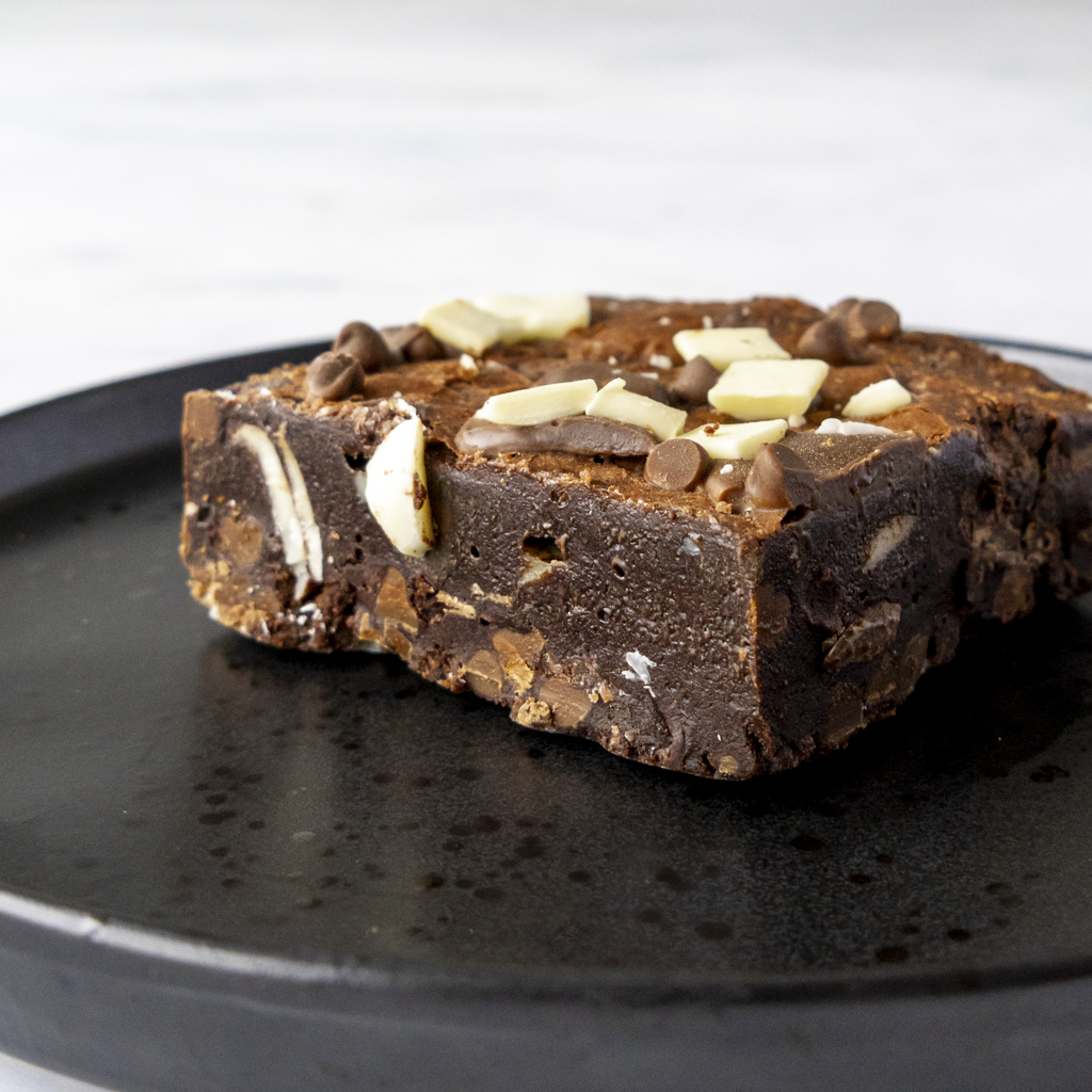 Chocolate brownie with three types of premium chocolate chips for chocolate lovers on a black plate