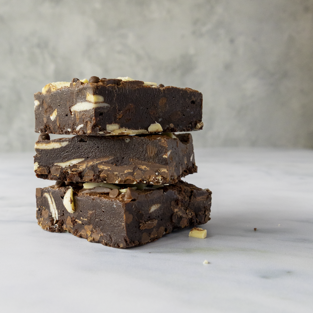 Close-up of a stack of chocolate fudge with triple chocolate chips by DoughGirl UK on a marble surface