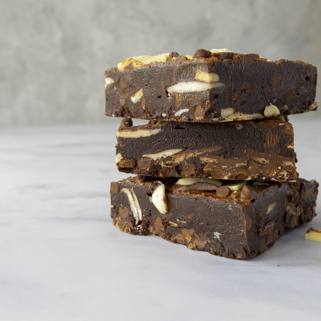 Stack of chocolate bars, with three types of premium chocolate milk, dark &amp; white chocolate, on a light gray background