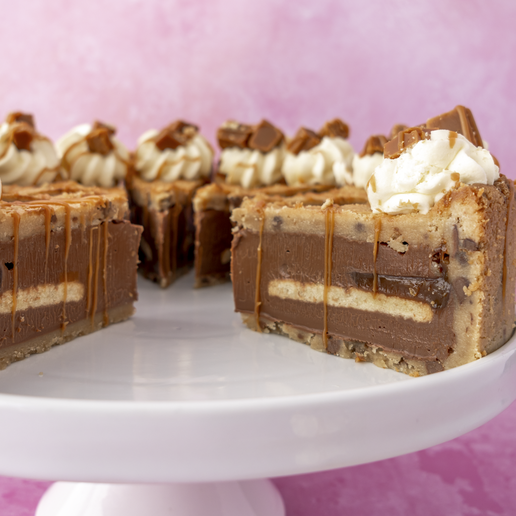 Layers of a Full Banoffee Cookie Pie by DoughGirl UK with white frosting on a pink background
