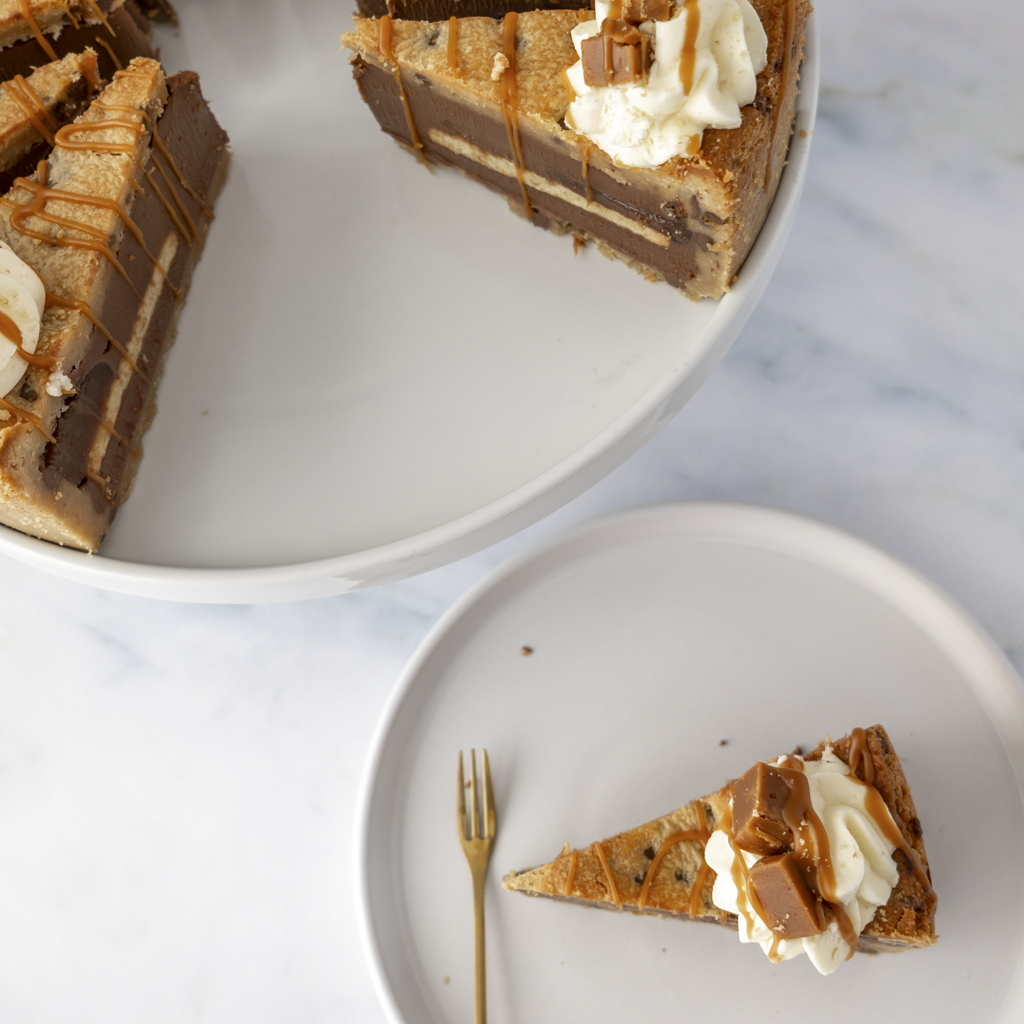 A slice of layered dessert by DoughGirl UK on white plates with a marble background