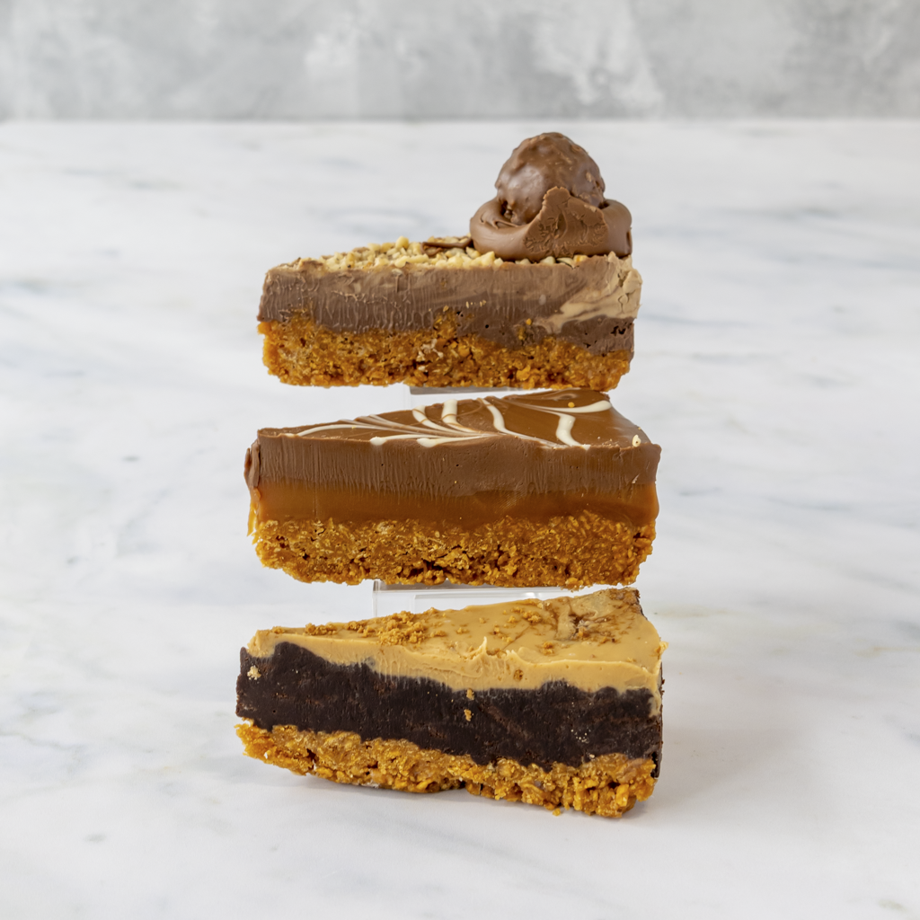 Three layered chocolate and cornflake pie slice stacked on a white marble surface