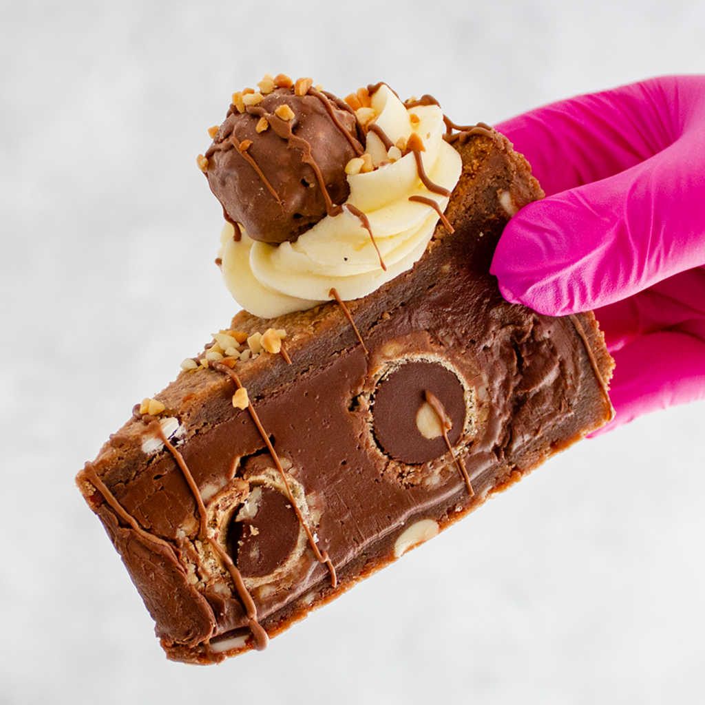 DoughGirl Hazelnut Truffle Cookie Pie with roasted hazelnuts and cream being held by a gloved hand on a white background