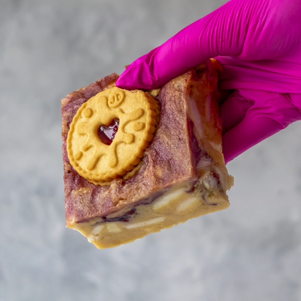 Hand holding a piece of Jammie Dodger Blondie Slab against a neutral background