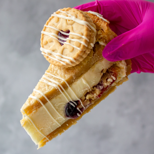 DoughGirl Jammie Dodger Cookie Pie with a pink glove holding it against a gray background