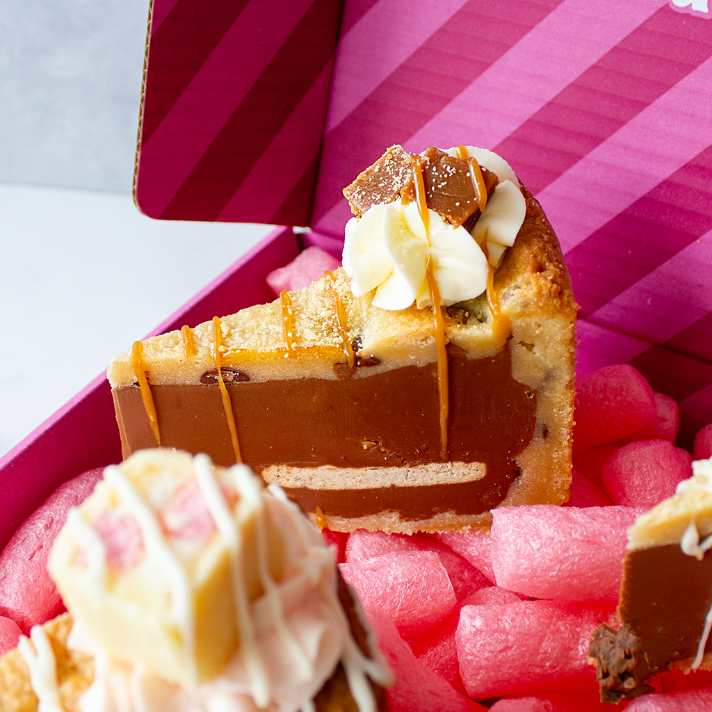 Slice of layered dessert with caramel and white cream on a pink striped gift box