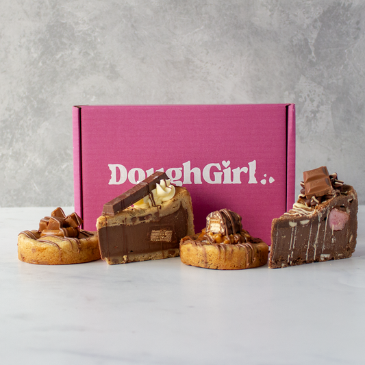 Five chocolate-dipped cookies and cookie pie slices in front of a pink 'DoughGirl' box on a grey background