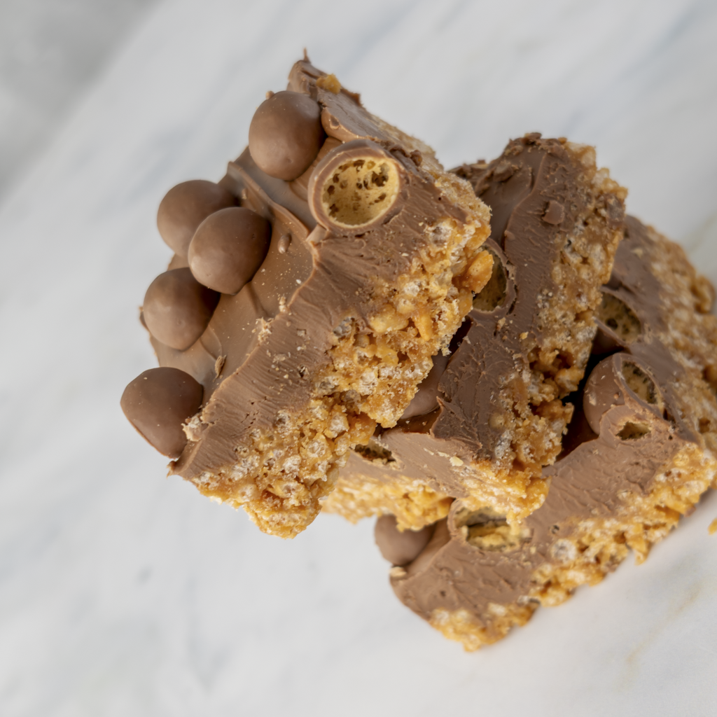 Malteser crispie slab slices stacked to show milk chocolate layer and crispie base