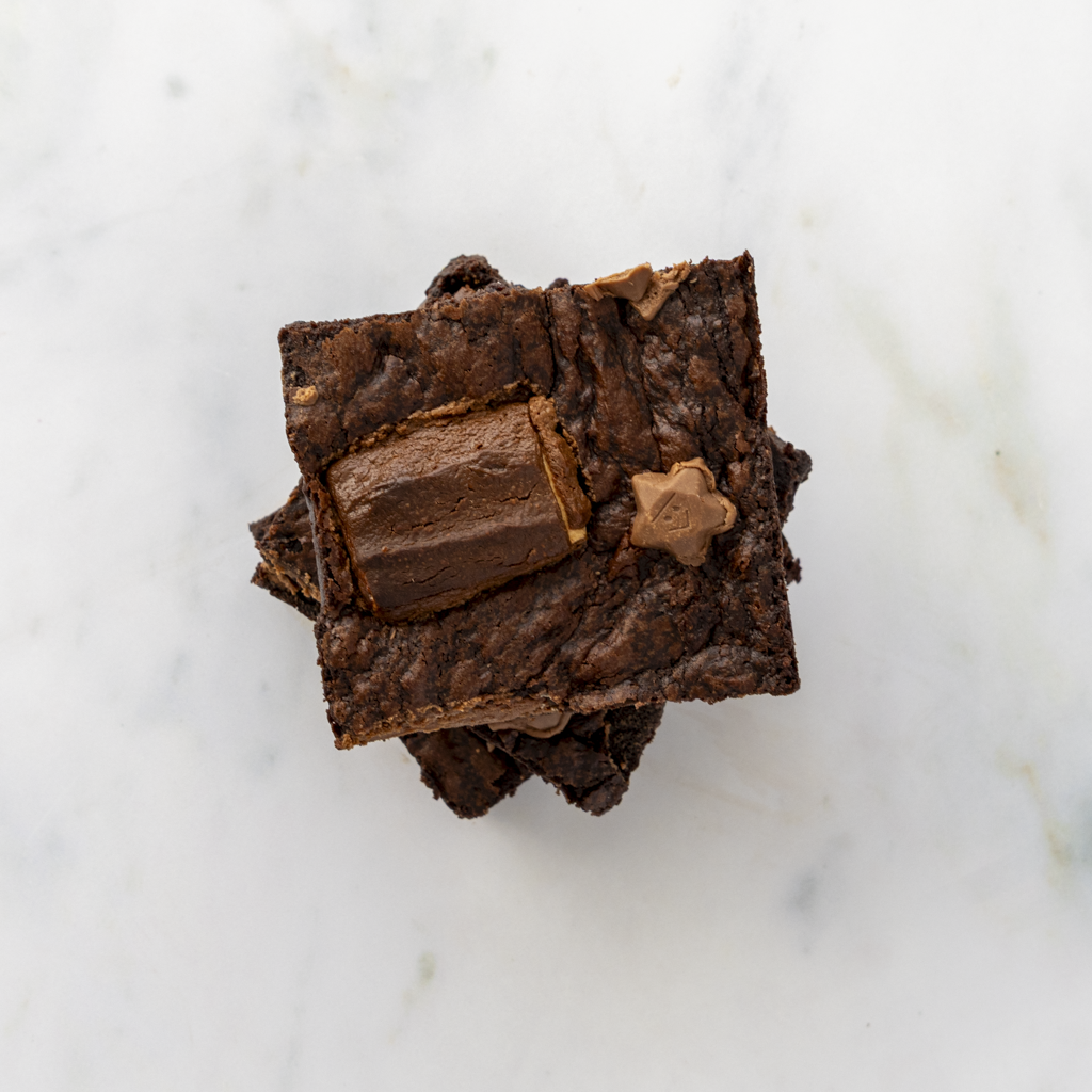 Stack of three brownie squares with chocolate chips on a marble surface
