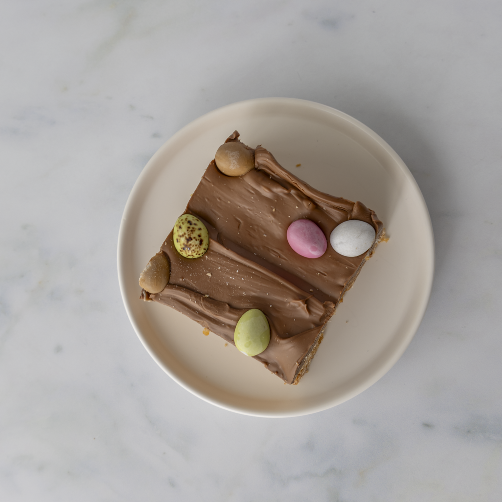 Indulgent Mini Egg Crispie Slab slice on plate with crunchy chocolate mini eggs