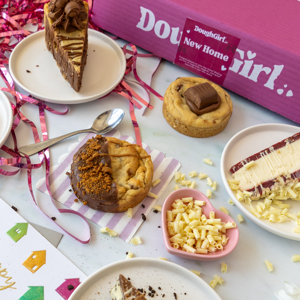 A styled flat-lay of baked goods and a pink box labeled 'DoughGirl New Home'.