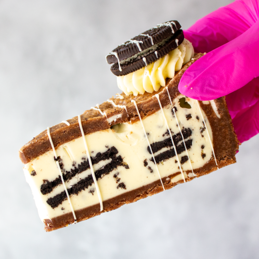 DoughGirl Oreo Cookie Pie Slice with Oreo biscuits held by a hand wearing a pink glove on a light gray background