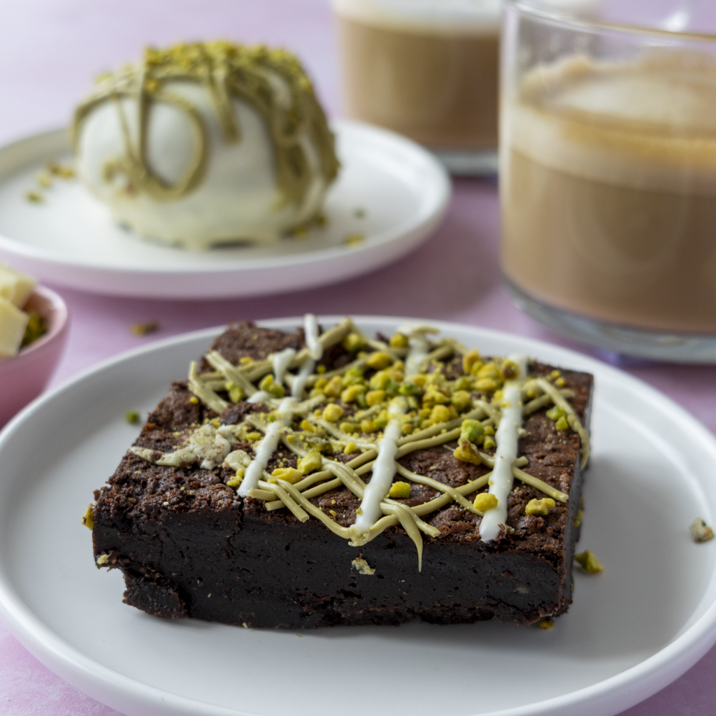 DoughGirl Pistachio Brownie Slab on a white plate with pistachio topping and creamy dessert