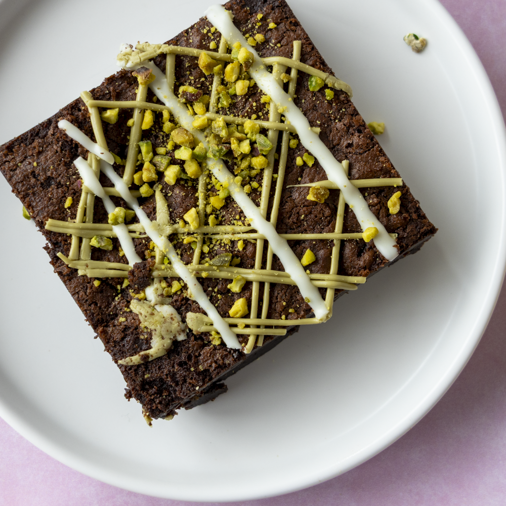 Overhead view of DoughGirl Pistachio Brownie Slab with white chocolate and pistachio drizzle