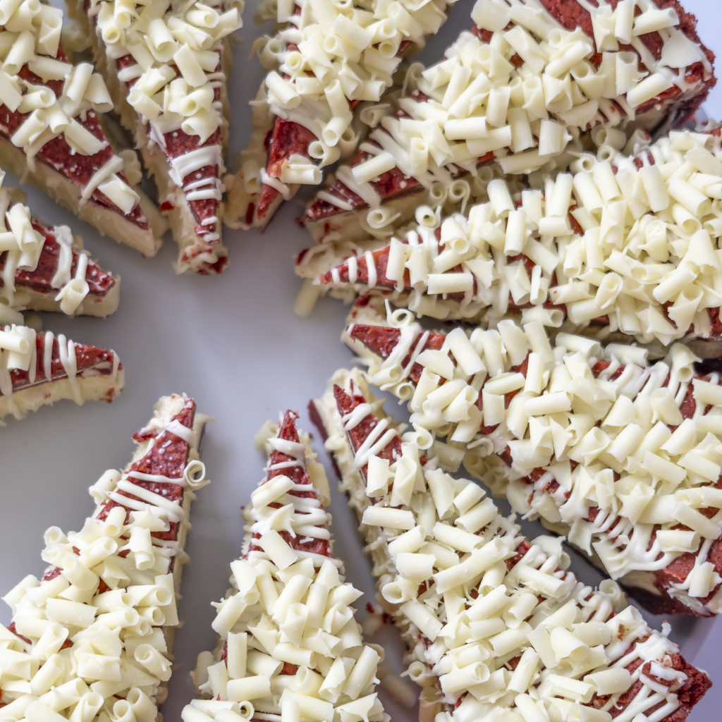 Red Velvet Cookie Pie Slices topped with white chocolate curls, arranged on a light gray background.