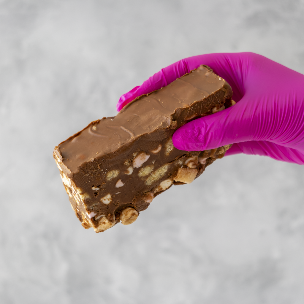 Handmade Rocky Mountain Rocky Road Slab held by a hand wearing a pink glove on a gray wall