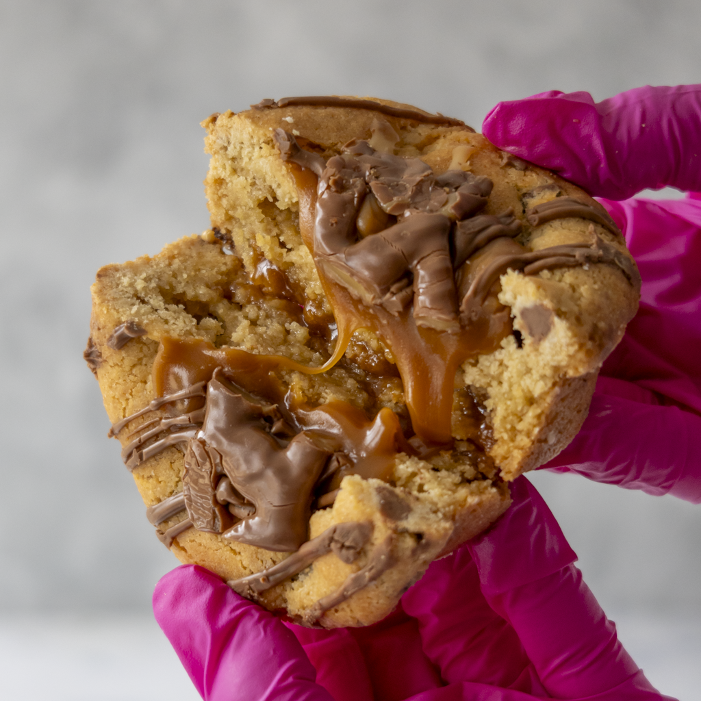 DoughGirl Curly Wurly Stuffed Deluxe Cookie broken open with gooey caramel centre