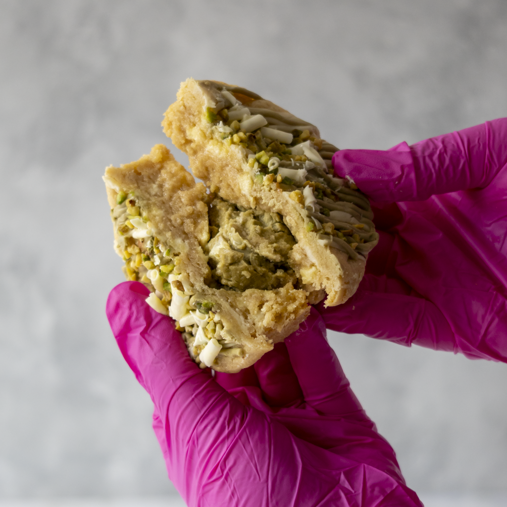 DoughGirl Pistachio & White Chocolate Stuffed Deluxe Cookie broken open with pistachio filling