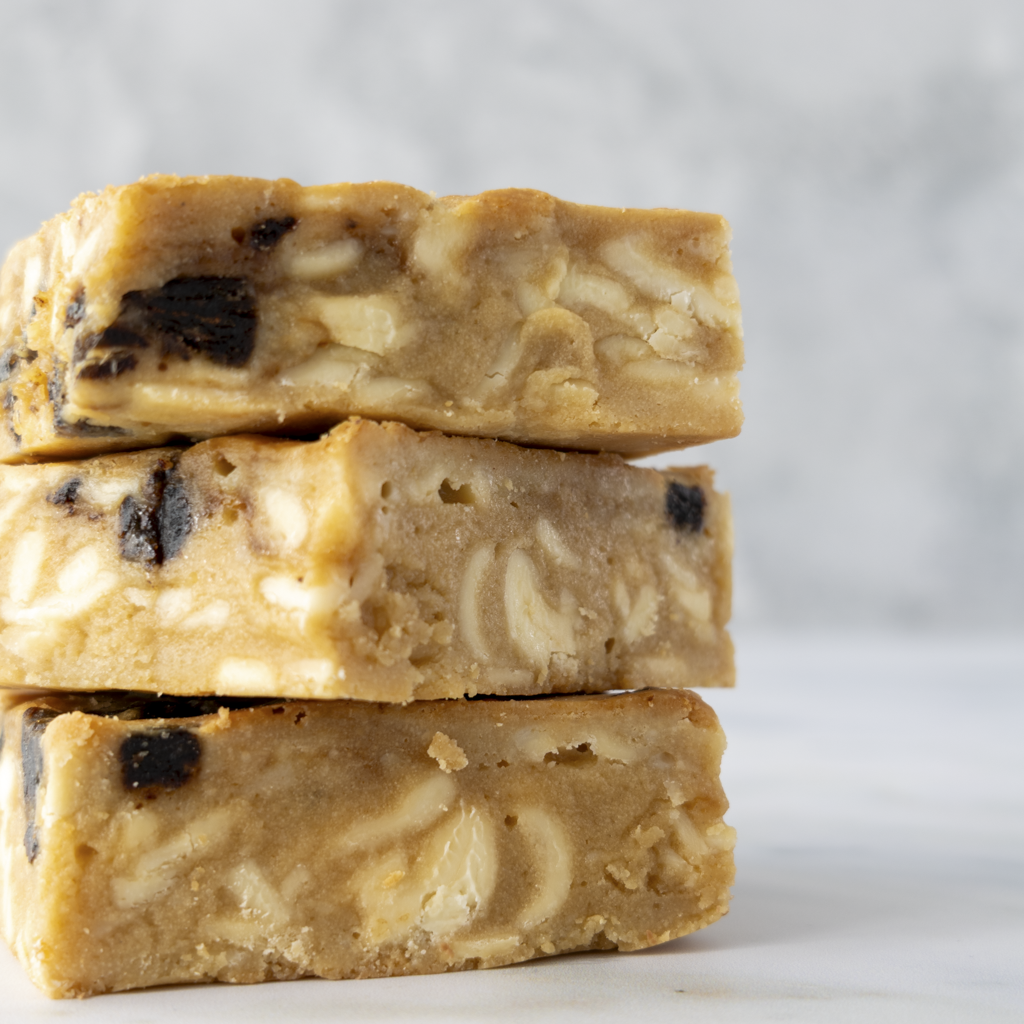 Close up of sticky toffee blondie slab showing gooey toffee sauce and soft date pieces